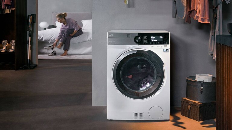 Жена, облегната на пералня със сушилня AEG.