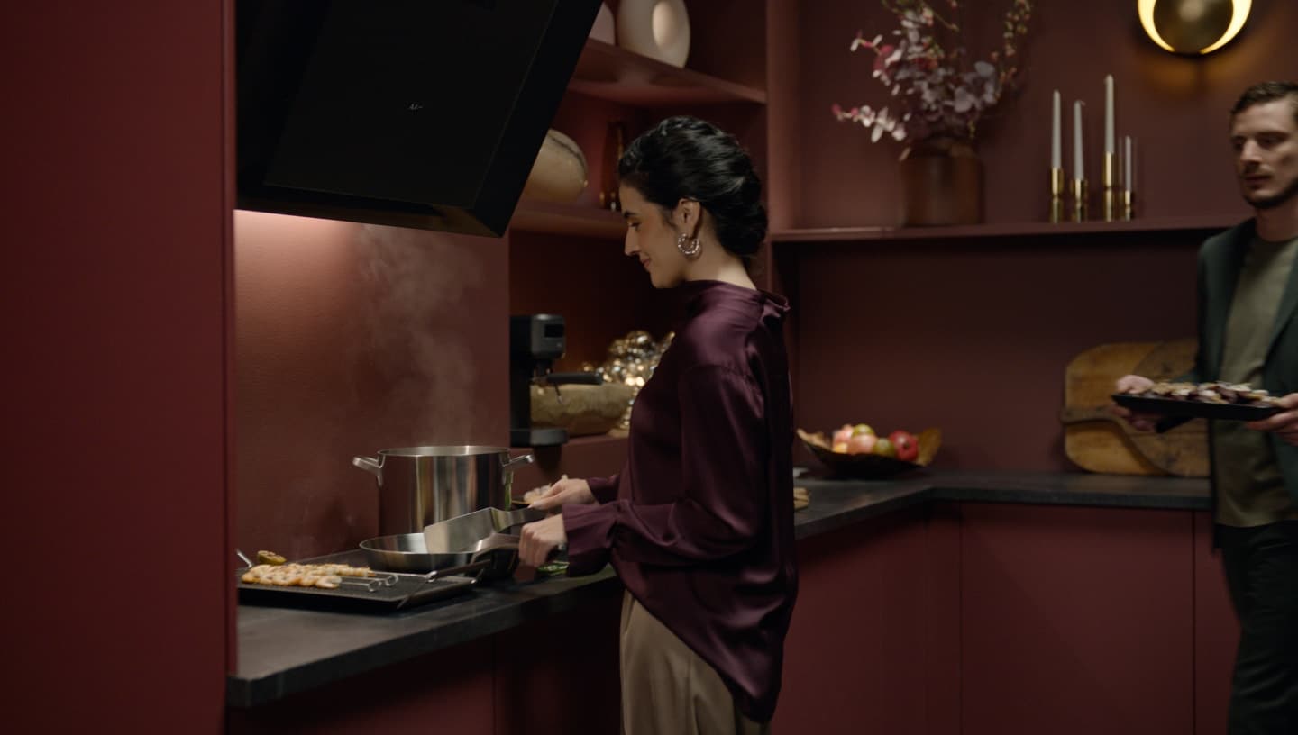 Жена и мъж приготвят храна в модерна кухня.