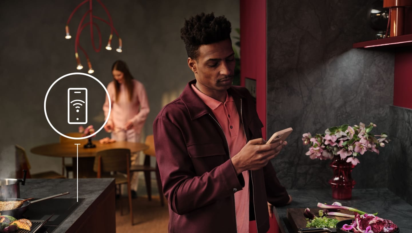 Мъж гледа телефона си в кухнята. 