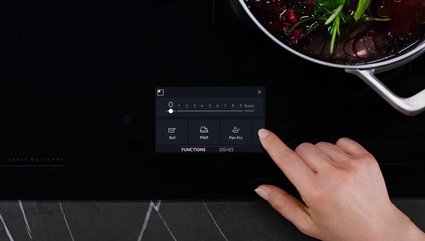 Пръст се допира до контролния панел на индукционен плот.