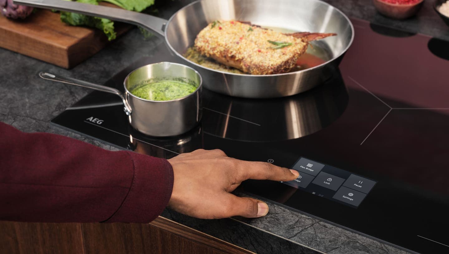 Пръст се допира до контролния панел на индукционен плот.