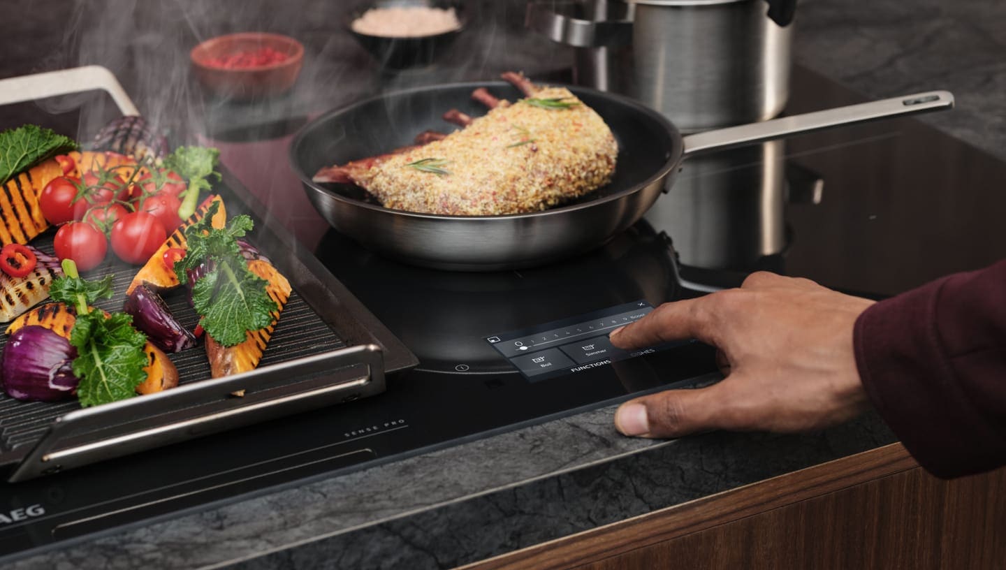 Пръст се допира до контролния панел на индукционен плот.