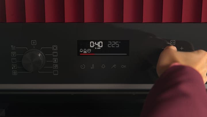 Човек натиска контролния панел на фурната.